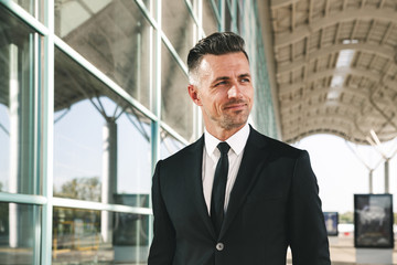 Sticker - Smiling businessman dressed in suit walking outside airport