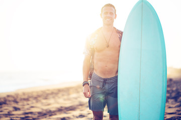 Wall Mural - Portrait of man surfer on the beach near the ocean standing with short surfboard and smiling