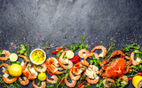 Fresh raw seafood - shrimps and crabs with herbs and spices on dark gray background. Copy space