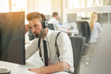 Worried or frustrated business man with headset working on computer in office