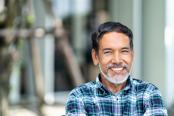 portrait of happy mature man with white, grey stylish short beard looking at camera outdoor. casual 