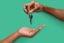 Black Man Handing Key Over To Person Hand
