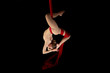 Joven bailarina realizando ejercicios de telas acrobáticas en estudio con fondo negro