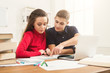 © Prostock-studio - Male and female students at table full of books