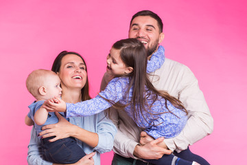 Happy mixed race family portrait smiling on pink background