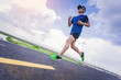 © Panumas - Young man jogging along the road. with cloudy sky as background
