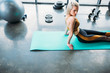 © LIGHTFIELD STUDIOS - side view of young athletic woman resting on fitness mat after work out at gym