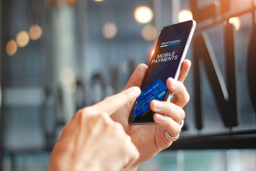 Aufkleber - Man using mobile payments for online shopping network connection on screen, Coffee shop background. All on screen and credit card are designed up.