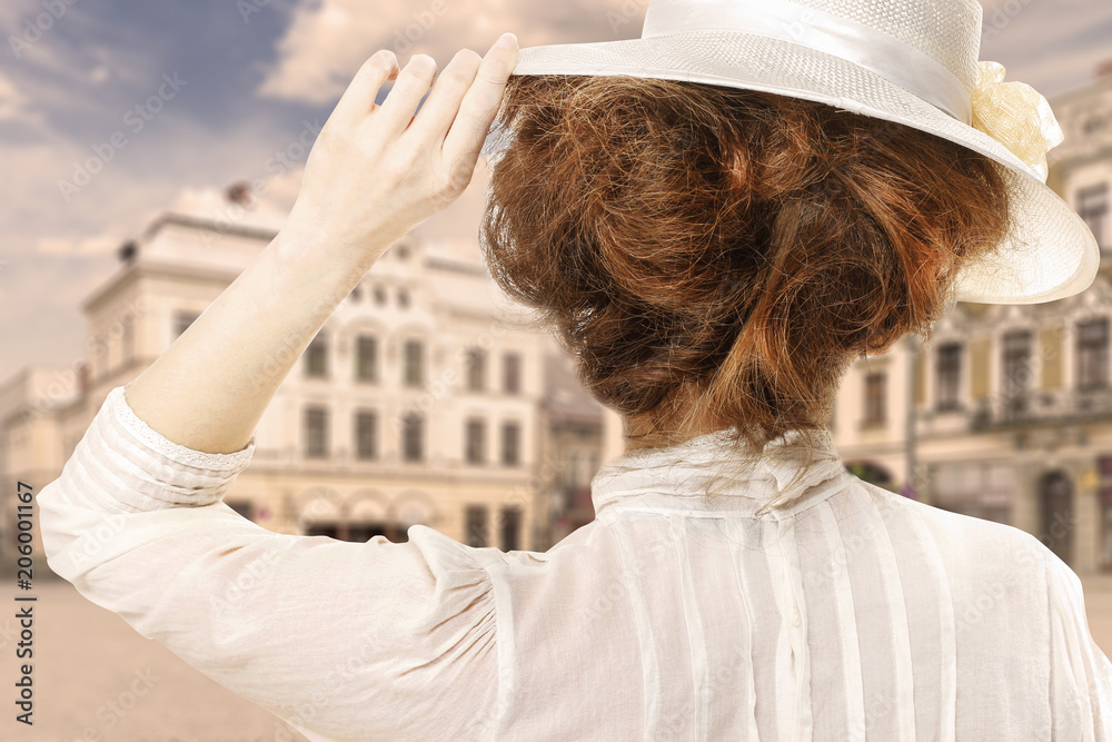 Retro styled picture of woman in victorian hat looking at the city street in Europe - obrazy, fototapety, plakaty 