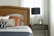 Black and brown pattern pillows setting on bed with brown leather headboard
