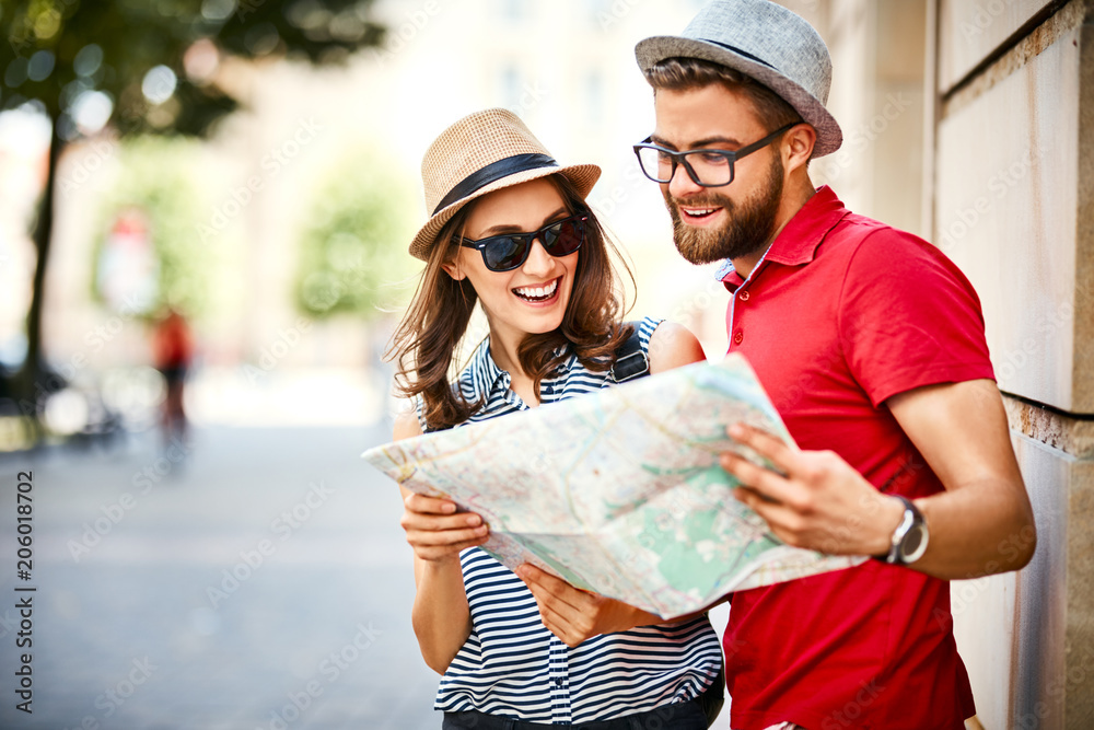 Young couple looking at map while on vacation during summer together - obrazy, fototapety, plakaty 