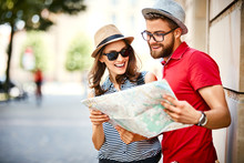 Young Couple Looking At Map While On Vacation During Summer Together