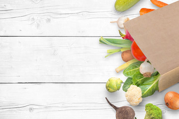 Paper bag with fresh market vegetables on whitee wooden table with copy space.