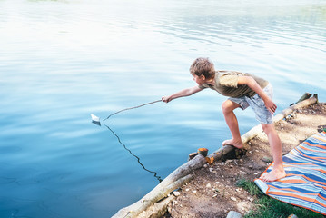 Wall Mural - Boy launches the paper boat in lake