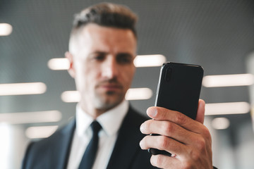 Canvas Print - Serious mature businessman looking at mobile phone