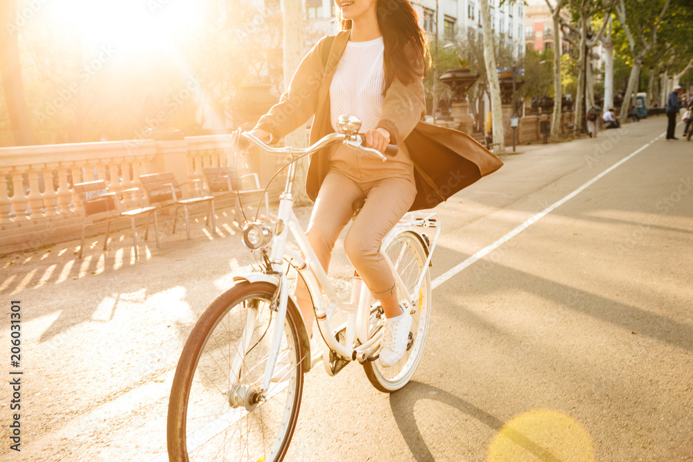 Cropped photo of young lady on bicycle on the street. - obrazy, fototapety, plakaty 