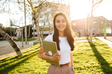 Sticker - Happy woman walking in park outdoors holding laptop