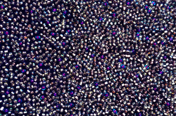 Glamorous background of shades of purple. A scattering of purple, pink, blue and red shiny balls. Beautiful shiny texture. Glitter glass balls sewn on a velvet belt. Imitation of diamonds.