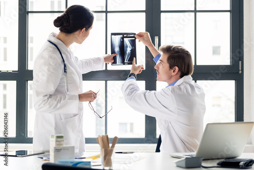 Fotomural Experienced male orthopedist helping his female colleague with the interpretatio