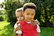 © Aksinia - Cute mixed twins brothers hugging each other in the park. Beatiful handsome kids.