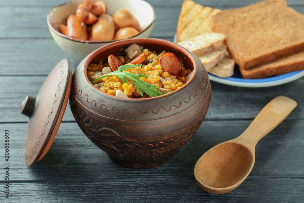 Pot with tasty lentils and sausages on table