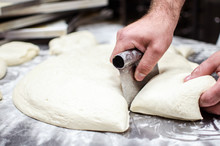 Male Baker Hands Using Kitchen Utensil To Divide Dough Prepared For Pizza Making.