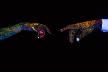 concept of connecting hands creative shooting in neon light male and female palms together stretch towards each other glow in the dark under ultraviolet