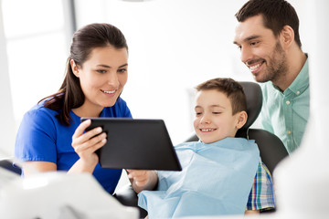 Canvas Print - medicine, dentistry and healthcare concept - dentist showing tablet pc computer to kid patient and his father at dental clinic