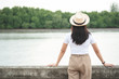 © AePatt Journey - Back view of happy hipster woman in hat standing and looking at river in evening sunset.