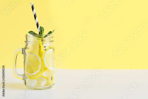 Fotomural Fresh summer fruits water or lemonade with lemon and mint on yellow background