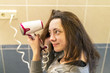 © jollier_ - Young woman with brown hair drying hair with electric blowdryer at home