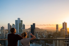 Couple Looking Above City Skyline With Sunset Sky 
