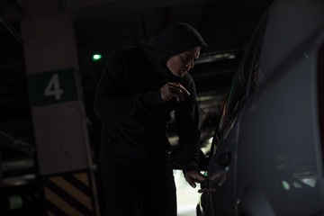 Wall Mural - side view of focused male thief intruding car by picklock