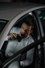 Wall Mural - high angle view of male private detective with coffee cup doing surveillance by binoculars from car