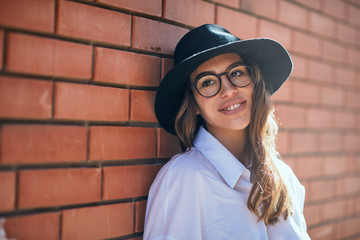 Wall Mural - Head shot of girl stasnding on the street. Girl wearing glasses and cap.