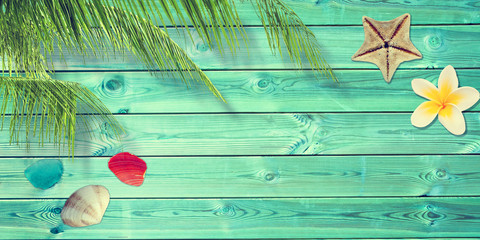 Wall Mural - Beach and summer background with blue planks, palm tree branch and seashells