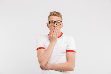 Canvas Print - Photo of scared guy in eyeglasses looking at you and covering mouth in fear or shock, isolated over white background