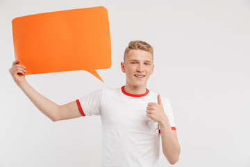 Sticker - Photo of happy advertiser boy wearing casual t-shirt holding copyspace orange poster for your text and showing thumb up, isolated over white background