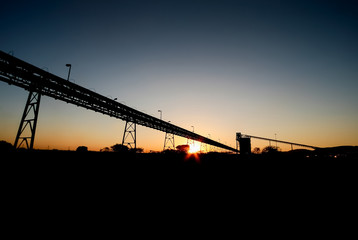 Silhouette of mining silo and conveyor belts at sunset	