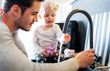 © leszekglasner - Handsome dad and his toddler child playing in the kitchen sink