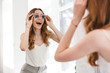 © Drobot Dean - Cheerful young woman trying on new sunglasses