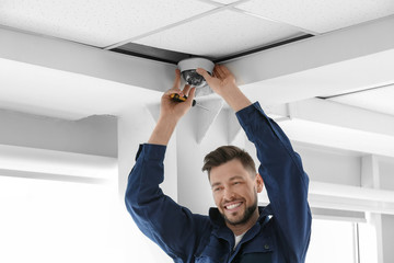 Wall Mural - Technician installing CCTV camera on ceiling indoors