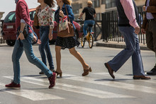 People Stranded And Distracted Crossing The Street In The Pedestrian Crossing At A Busy Intersection Crowded And Crowded In The Midst Of Traffic Only Showing Up The Legs And Feet. Walking And Talking 