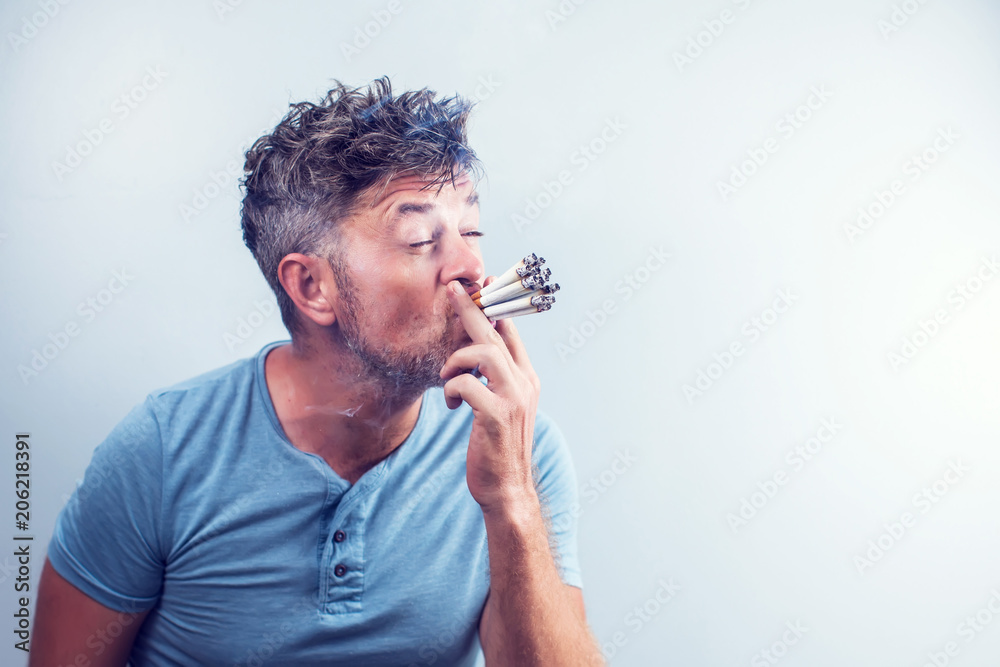 man with lots of cigarettes in his mouth Young man with many cigarettes in his mouth Stock Photo