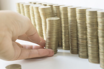 Woman's hand put money coins to stack of coins, Saving money concept.