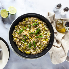 Wall Mural - risotto with asparagus in a frying pan on a white marble table.