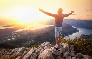 Happy man in the mountains looking at the sunset with open hands