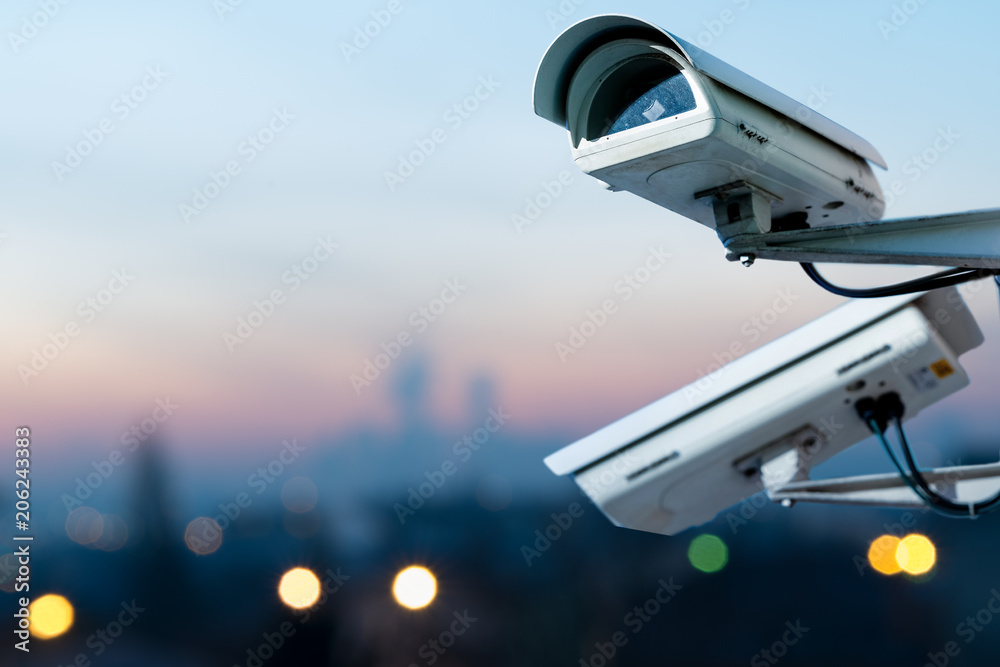 security CCTV camera monitoring system with panoramic view of a city on blurry background - obrazy, fototapety, plakaty 