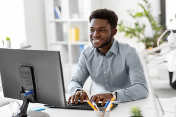 business, people and technology concept - african american businessman with computer working at offi