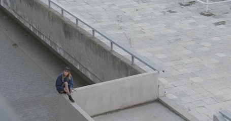 Poster - Beautiful young woman waiting someone and listening to music on her smartphone. 4K video shooting by handheld gimbal